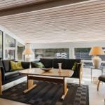 Wohnzimmer mit Sofa, Tisch und Fenstern.