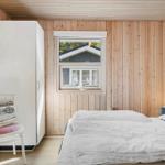 Schlafzimmer mit Holzwand, Bett, Kleiderschrank und Fenster mit Blick auf Haus.