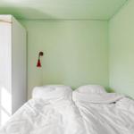 Schlafzimmer mit Bett, Kleiderschrank und Wandlampe.