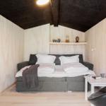 Schlafzimmer mit Bett, Nachttisch und Sessel unter schwarzem Dach