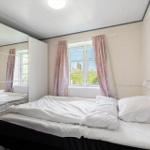 Schlafzimmer mit Bett, Fenster und Schrank. Vorhang und Decke sind rosa.