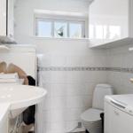 Badezimmer mit Waschbecken, Toilette und Waschmaschine. Fenster mit Blick nach draußen.