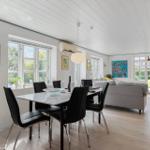 Essbereich mit Tisch und Stühlen, Wohnbereich mit Sofa und Fenstern.