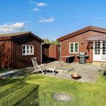 Holzhütte mit Grill und Feuerkorb im Garten unter blauem Himmel.