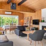 Wohn- und Essbereich mit Kamin, TV und großem Fenster. Holzwände und -decke.
