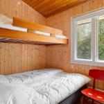 Zimmer mit Schlafcouch und obere Schlafcouch, roter Stuhl und Fenster mit Blick auf Wald.