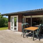 Terrasse mit Tisch und Stühlen vor einem Haus mit Holzfassade und Glasfront.