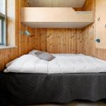 Schlafzimmer mit Doppelbett, Holzwand und Fenster. Oben Schlafplatz mit Kletterwand.
