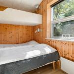 Schlafzimmer mit Bett, Holzwand und Fenster mit Blick auf Bäume.