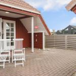 Terrasse mit zwei weißen Stühlen vor rotem Haus mit Dach und Fenstern.