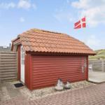 Rotes Holzhaus mit Terrasse und dänischer Flagge. Holzumzäunung und Steinplatten.