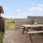 Terrasse mit Holztisch und Bänken, umgeben von Holzgeländer und Grasfläche.