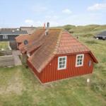 Rotes Holzhaus mit Schieferdach in grüner Umgebung.