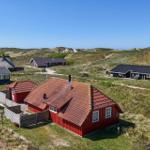 Rotes Haus mit rotem Dach in einer grünen Landschaft mit weiteren Häusern.