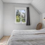 Schlafzimmer mit Bett, Fenster und Stuhl. Wandbild und Lampe sind sichtbar.