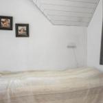 Ein Schlafzimmer mit Bett, Wandbildern und Fenster mit Vorhang.