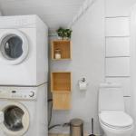 Badezimmer mit Waschmaschine, Trockner, Toilette und Dusche.