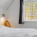 Schlafzimmer mit Bett, Stuhl und Fenster mit Pflanze.