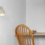 Holzstuhl und Tisch in Ecke mit Wandlampe