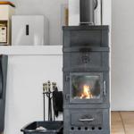 Schwarzer Kaminofen mit brennendem Feuer und Zubehör in Küche