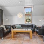 Wohnzimmer mit Leder沙发, Holztisch und Kaminofen. Weiße Wände und Holzdecke.