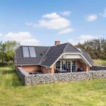 Ein Haus mit Steinmauer, Terrasse und Solaranlage im Grünen.