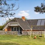Ein Haus mit Steinmauer, Schaukel und Solaranlage auf dem Dach.