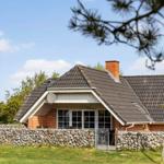 Haus mit Steinmauer und Dachgaube unter blauem Himmel