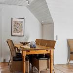 Essbereich mit Holztisch, Rattanstühlen und Wandbild unter schrägem Dach