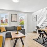 Wohn- und Essbereich mit Sofa, Tisch und Treppe.