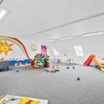 Großer Spielraum mit bunten Spielen, Rutschbahn und Wandmalerei.