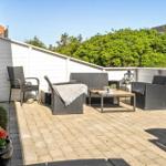 Terrasse mit Sitzgruppe und Tisch, umgeben von weißen Wänden und Grün.