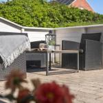 Terrasse mit Gartenmöbeln, Tisch und Decke. Hintergrund: grüne Hecke und Hauswand.