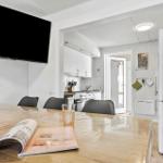 Essbereich mit Holztisch, Fernseher und Blick in die Küche.