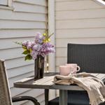 Außenbereich mit Tisch, Stühlen, Blumen und Tassen.