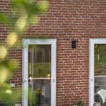 Terrasse mit Tisch und Stühlen vor rotem Backsteinhaus mit Fenstern.