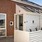 Wohnhaus mit weißen Holzwänden und Terrasse. Tür offen, Blick in Küche.