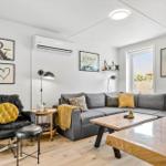 Wohnzimmer mit grauem Sofa, Holztisch und schwarzer Sitzgelegenheit.