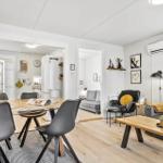 Wohn- und Essbereich mit Sofa, Esstisch und Küchenbereich im Hintergrund.