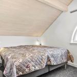 Schlafzimmer mit Dachschrägen, Bett mit floraler Decke und Bogenfenster.