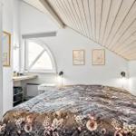 Schlafzimmer mit Dachschrägen, Bett mit Blumenbezug, Fenster und Schrank.