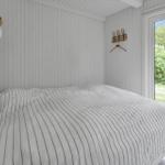 Schlafzimmer mit Bett, weißen Wänden und Blick auf Garten.