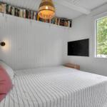 Schlafzimmer mit Bett, Fernseher und Bücherregal an der Wand.