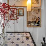 Tisch mit blau-weißen Fliesen, Vase mit roten Zweigen und Wanddekoration.