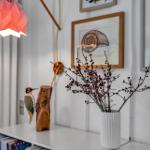 Ein Regal mit Vase, Vogeldekoration und Bildern an der Wand.