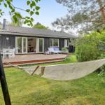 Hängemattenschaukel im Garten neben einer Holzhütte mit Terrasse und Gartenmöbeln.