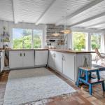 Küche mit Holzoberflächen und Blick auf Garten. Wohnbereich mit Kamin und Sitzgelegenheit.