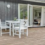 Terrasse mit weißem Tisch und Stühlen, Schiebetür führt ins Haus.