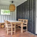 Holztisch mit Stühlen und Bank unter einem Korblicht.