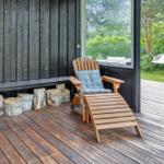 Terrasse mit Holzstuhl, Kissen und Baumstumpfen. Hintergrund: Grünfläche und Hängemattensitz.